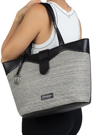 Black and white woven tote bag with a structured shape, leather detailing, a clasp closure, and a logo plate on the front.