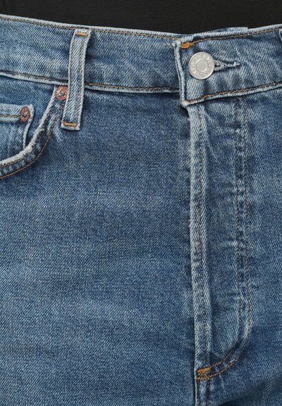 Mėlynos džinsinės kelnės su užtrauktuku ir sagos uždarymu, kontrastingai oranžine siūle, priekinėmis kišenių detalėmis. Audinys lygus su šiek tiek blizgesio.