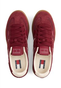 Rode suède sneakers met veters, gumrubberen zool, witte logo-accenten en merkembleem. Gestructureerd bovenwerk met contrasterende details.