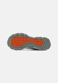 Gray sneaker sole with an intricate textured pattern; red accents in a grid layout; rubber material with a slightly speckled appearance.