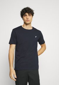 Navy blue cotton t-shirt with a crew neckline and short sleeves, featuring a small white logo on the left chest area.