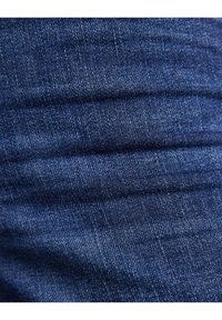 Tejido de denim azul oscuro con una textura suave, que muestra un patrón de sarga clásico y sutiles detalles de costura en toda su superficie.
