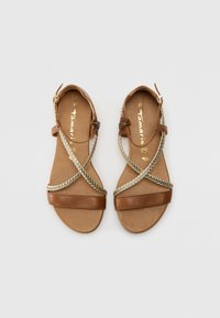 Sandali in pelle marrone con cinturini intrecciati dorati, suola piatta e fibbia laterale. La soletta presenta un logo del marchio dorato. Misura 37.