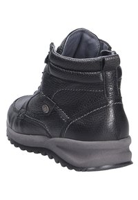 Bottine noire en cuir avec surface texturée, coutures renforcées et semelle en caoutchouc grise. Elle présente un logo sur le côté et un col rembourré.