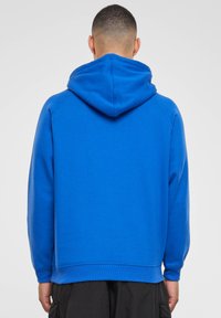 Sudadera azul hecha de una mezcla de algodón suave, con una capucha grande y puños acanalados, con una textura suave y un corte holgado.