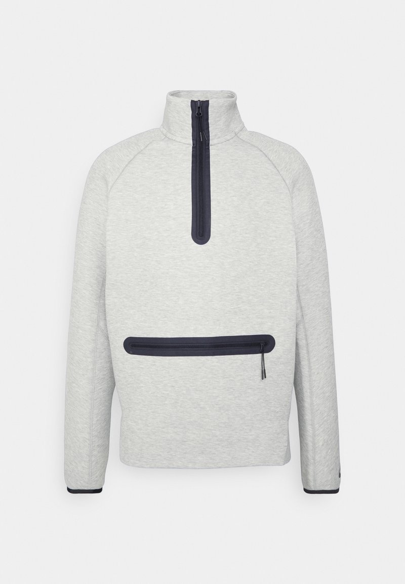 Pull léger en polaire gris clair avec un col montant, fermeture zippée sur la moitié avant et une poche zippée horizontale bleu marine. Poignets ajustés avec des accents bleu marine.
