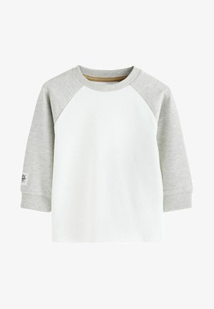 Camiseta de manga larga con cuerpo blanco y mangas en raglán grises. Presenta un cuello y puños de canalé. Material de algodón suave con una etiqueta en la manga.