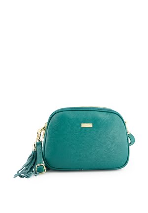 Teal leather crossbody bag with gold hardware, zip closure, and a decorative tassel. Rounded shape with textured surface and logo detail.