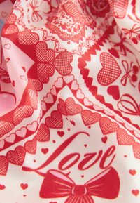 Piros és rózsaszín szövet mintával, amely szíveket, masnikat és a "Love" (Szerelem) szót ábrázolja, texturált, réteges megjelenést kölcsönözve.