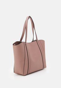 Sac fourre-tout en cuir rose doux avec double bandoulière et détails de couture verticale, présenté sur un fond blanc.