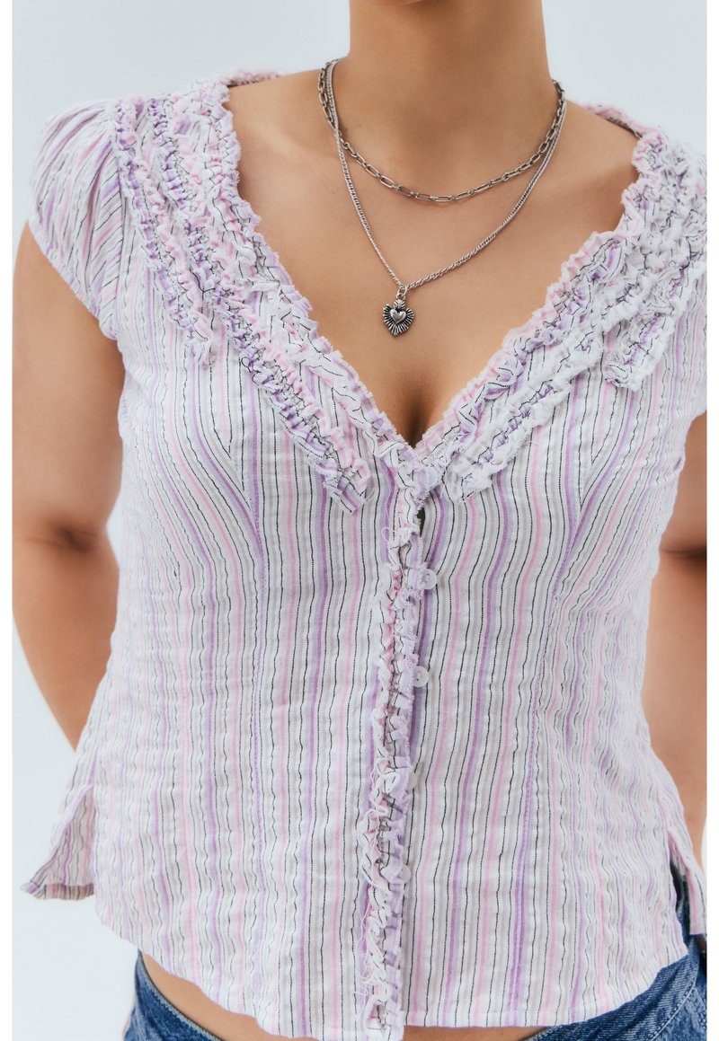 Blus i vitt och lavendelrandigt med rynkad halsringning, korta ärmar och knappstängning. Mjuk tyg med en texturerad yta.