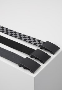 Drie riemen met een zwart- en grijs kleurenpalet. Eén heeft een ruitpatroon, allemaal hebben ze platte zwarte metalen sluitingen. Gestructureerde geweven stof.