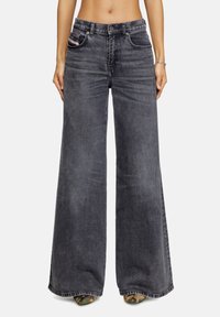 Jean large gris foncé en denim, avec une taille haute, un design à cinq poches et des accents de couture le long des coutures.
