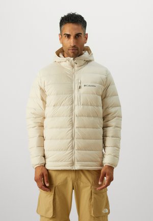 Beige dunjakke med hette, quilted design, frontglidelås og logo på venstre bryst. Brukt med brune cargobukser.