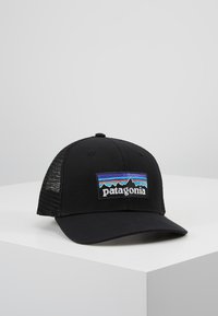 Căciulă de tip trucker de culoare neagră, cu un front structurat, panouri din plasă și un logo brodat colorat Patagonia cu un design montan.