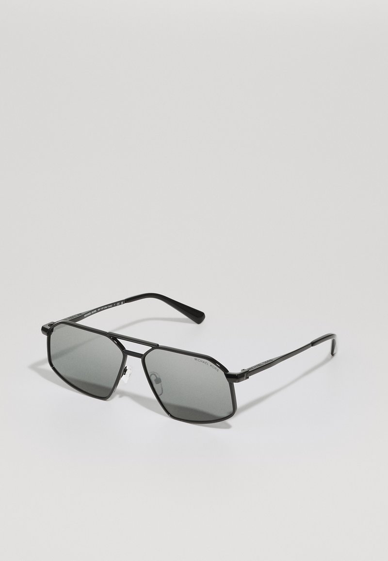 Occhiali da sole in stile black metal con lenti grigie. Forma ottagonale, aste sottili, logo su un lato e naselli trasparenti per un comfort ottimale.