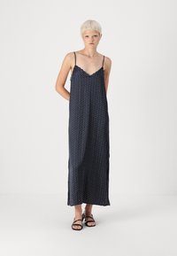Long navy dress with white and red polka dots, lace trim along the neckline, and side slits. Lightweight fabric with adjustable straps.