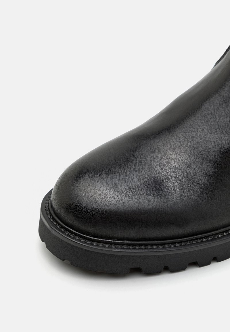 Stivale in pelle nera alla caviglia con punta arrotondata, finitura texture e suola in gomma spessa con scanalature profonde per una migliore aderenza.