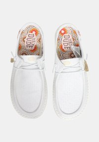 Witte casual schoenen met een gestructureerde canvas buitenkant. Voorzien van een ronde neus, vetersluiting en een patroon in de binnenzool. Accenten zijn onder andere een kwastje.