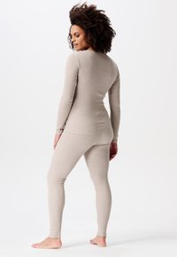 Beige thermoshirt en leggings, vervaardigd uit een zachte, rekbare stof, met lange mouwen en een smalle tailleband.