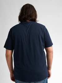 Námořnická modrá bavlněná tričko s krátkým rukávem, rovný spodní lem a klasický střih, z pohledu zezadu. Žádné viditelné vzory nebo grafika.