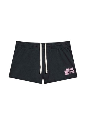 Czarne spodenki kąpielowe ze białym sznurkiem i różowym napisem „Miami Beach” oraz kwiatem hibiskusa na lewej nogawce.