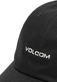 Gorra negra de algodón, con visera curva y un logo bordado en blanco "VOLCOM" en la parte frontal. Tela texturizada, diseño de seis paneles.