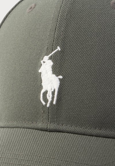 Alyvuogių žalios spalvos kepurė iš tekstūruotos medžiagos, priekyje – balta siuvinėta arklio ir raitelio logotipo. Išlenktas snapelis.