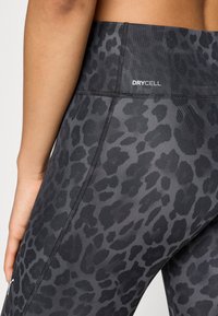 Κολάν με μαύρο και γκρι σχέδιο και λεία, ελαστική υφή. Διαθέτει ψηλή μέση με το λογότυπο «DRYCELL» και ραφές σε αντίθετο χρώμα.