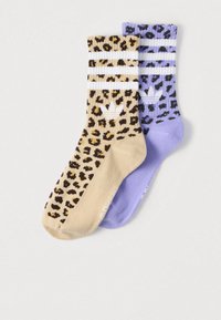 Divi viduslīmeņa garuma zeķu pāri, viens bēšs un viens lavandas krāsā, abi ar leoparda rakstu, baltām svītrām un baltu Adidas logotipu uz aproces.
