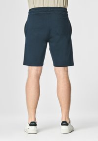 Shorts in cotone blu navy con vita elastica, tasche laterali e una tasca posteriore. Tessuto liscio e design a lunghezza ginocchio.
