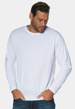Weißes langärmeliges T-Shirt aus Baumwolle mit rundem Ausschnitt und minimalistischem 'JP'-Logo auf der Brust, kombiniert mit blauen Jeans.