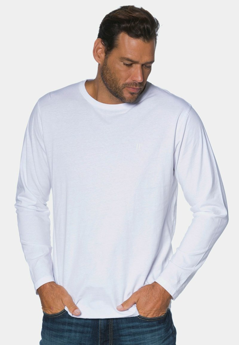 Weißes langärmeliges T-Shirt aus Baumwolle mit rundem Ausschnitt und minimalistischem 'JP'-Logo auf der Brust, kombiniert mit blauen Jeans.