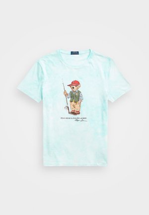 Lichtblauw tie-dye T-shirt met een vissersthema beer die een rode pet en vest draagt, met een hengel in de hand, Polo Bear van Ralph Lauren logo eronder.