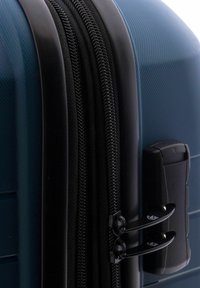 Maleta rígida de color azul oscuro, con doble cremallera negra, superficie texturizada y un asa lateral resistente para un transporte seguro.