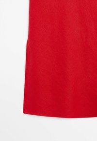 Roter Stoff mit glatter Textur, gezeigt als Nahaufnahme vor einem schlichten weißen Hintergrund.