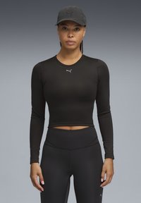 Czarny krótki top z długim rękawem wykonany z elastycznego materiału, z elastycznym dołem i małym logo na piersi. Do zestawu dołączone czarne legginsy.