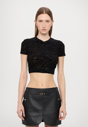 T-shirt noir court avec un motif de rayures zèbres texturé, manches courtes et col rond, associé à une mini-jupe en cuir noir.