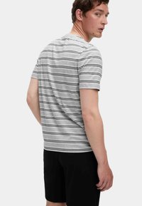 Stripet grå t-shirt med sorte vandrette linjer, korte ærmer og rund halsudskæring, parret med sorte shorts. Blødt, afslappet stof.