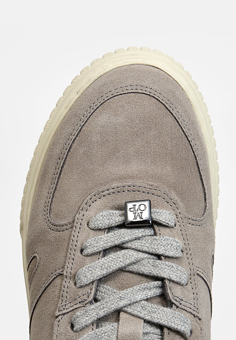 Graue Wildleder-Sneaker mit strukturierten Oberflächen, cremefarbener Gummisohle, flachen grauen Schnürsenkeln und einem silbernen Logo-Akzent auf der Zunge.