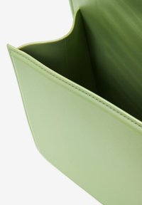 Borsa in pelle verde con una texture liscia, caratterizzata da un'ampia apertura e bordi curvi. Cuciture pulite lungo le cuciture.