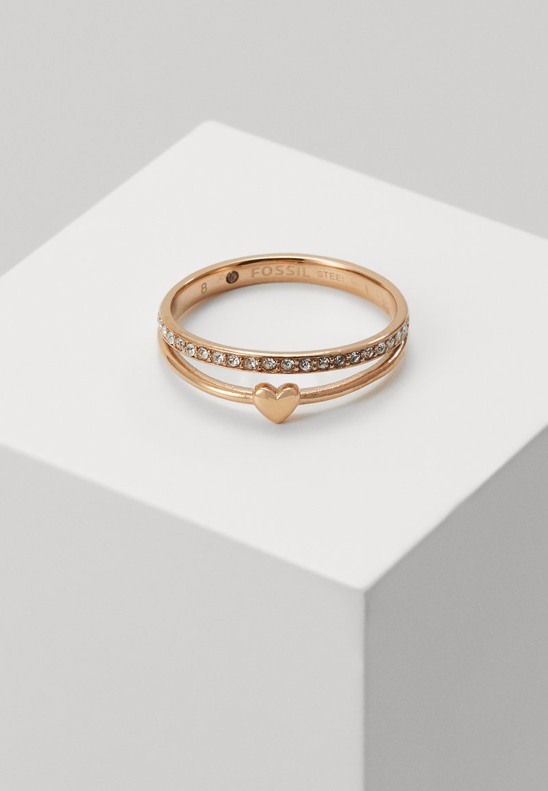 Anello in oro rosa con finitura lucida, con un accento a forma di cuore e una fila di cristalli trasparenti lungo una banda. Misura 8. Realizzato in acciaio inossidabile.