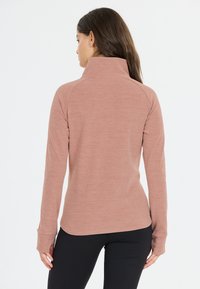 Langarm-Pullover in Hellrosa, mit hohem Kragen, weichem Material und Daumenlöchern an den Ärmeln. Rückansicht mit glatten Nähten.