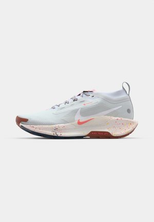 Nike hardloopschoenen in lichtgrijs met een felrode en gele spetters op de zool. Voorzien van vetersluiting en een gevoerde tussenzool.