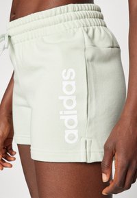Světlé zelené bavlněné šortky s elastickým pasem. Na boku bílé nápisy "adidas" a boční rozparky na lemu.