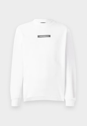 Hvit langermet crew neck sweatshirt med ribbede mansjetter og kant, med en liten rektangulær svart logopatch som leser "VERSACE JEANS COUTURE" på brystet.