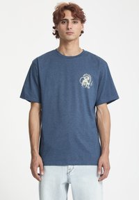 Camiseta de algodón azul con mangas cortas, escote redondo y un diseño gráfico frontal que presenta "ANTI-CRUZ" en blanco.