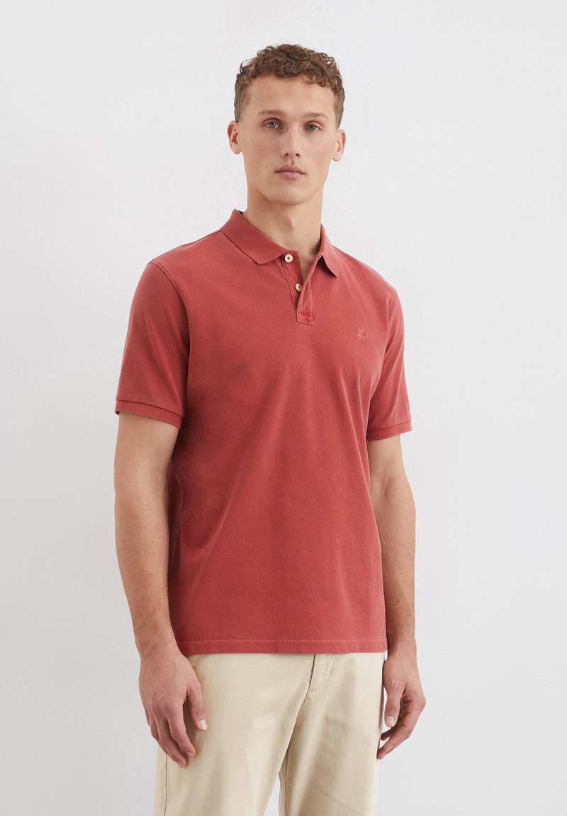Rotes Polohemd aus Baumwolle mit einer Knopfleiste mit drei Knöpfen und kurzen Ärmeln. Verfügt über ein kleines gesticktes Logo auf der Brust.