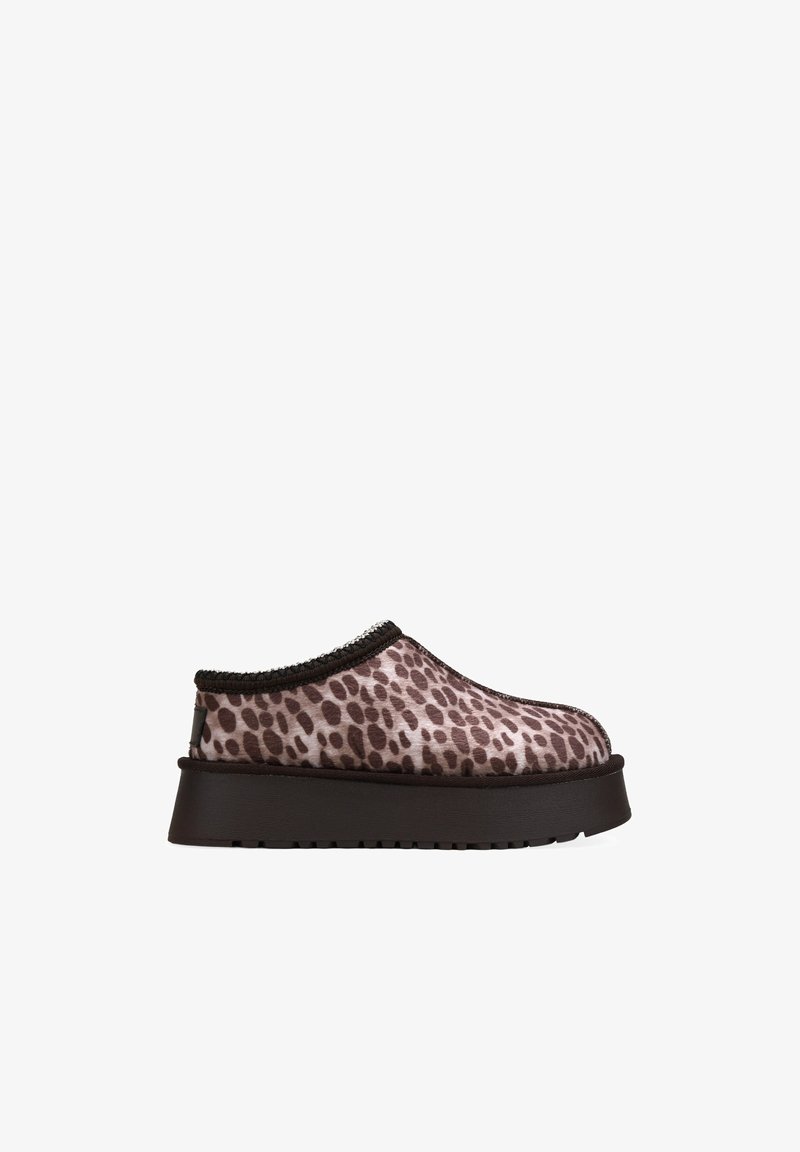 Zapato tipo slip-on con estampado de leopardo, parte superior de tela suave, costuras en contraste y suela de goma marrón gruesa. Diseño de punta redondeada.