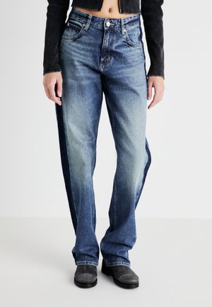 Light blue denim jeans with a faded design, straight-leg cut, five pockets, and a zip fly. Worn with a black cropped jacket.